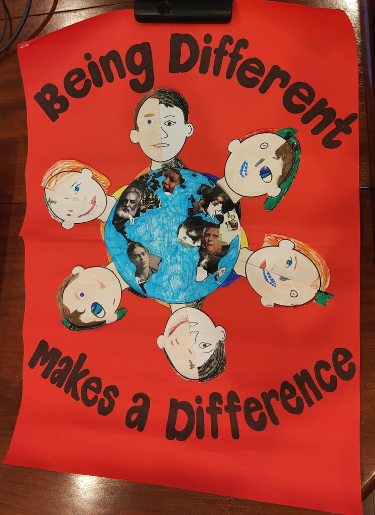 A cardboar with a drawing of children's faces surounding planet earth