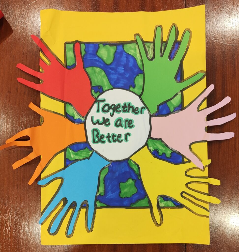 A cardboar with collage of planet earth and cardboard hands sticked on it