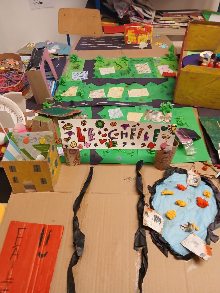 A colorful, child-created art piece of an accessible playground made from cardboard.